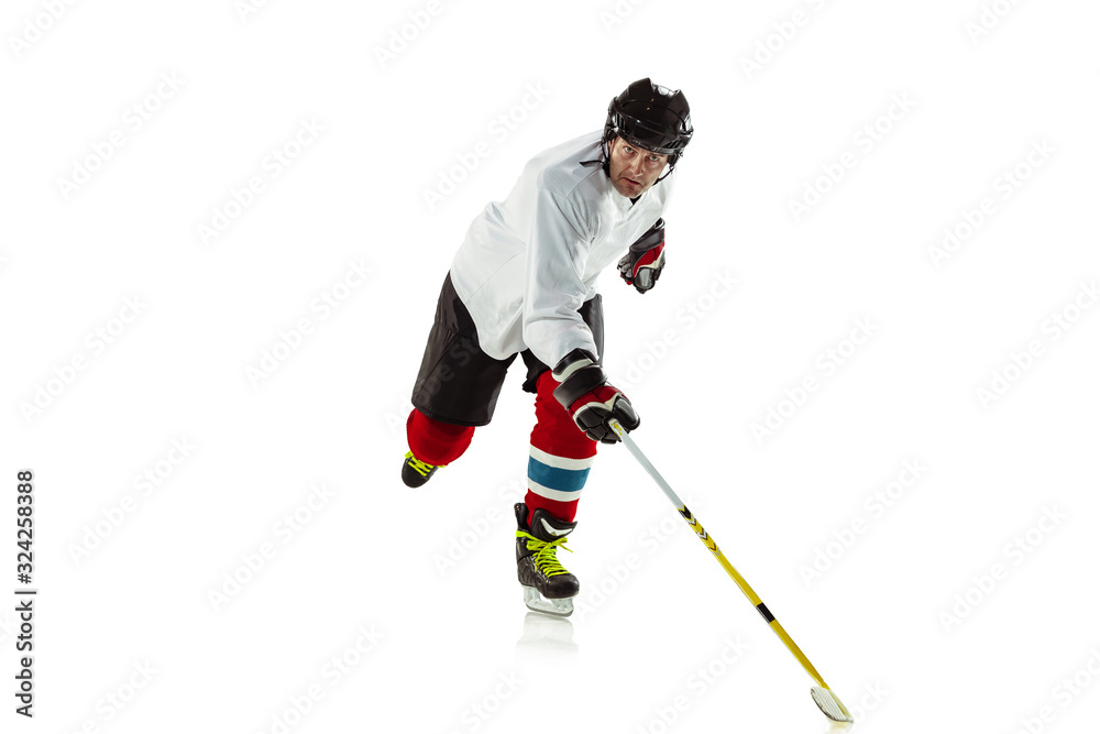 Obraz premium Scoring. Young male hockey player with the stick on ice court and white background. Sportsman wearing equipment and helmet practicing. Concept of sport, healthy lifestyle, motion, movement, action.