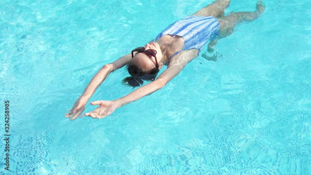 top view beautiful woman swiming on back, enjoying and relaxing in swimming pool At Luxury hotel spa top view beautiful woman swiming on back, enjoying and relaxing in swimming pool At Luxury hotel spa