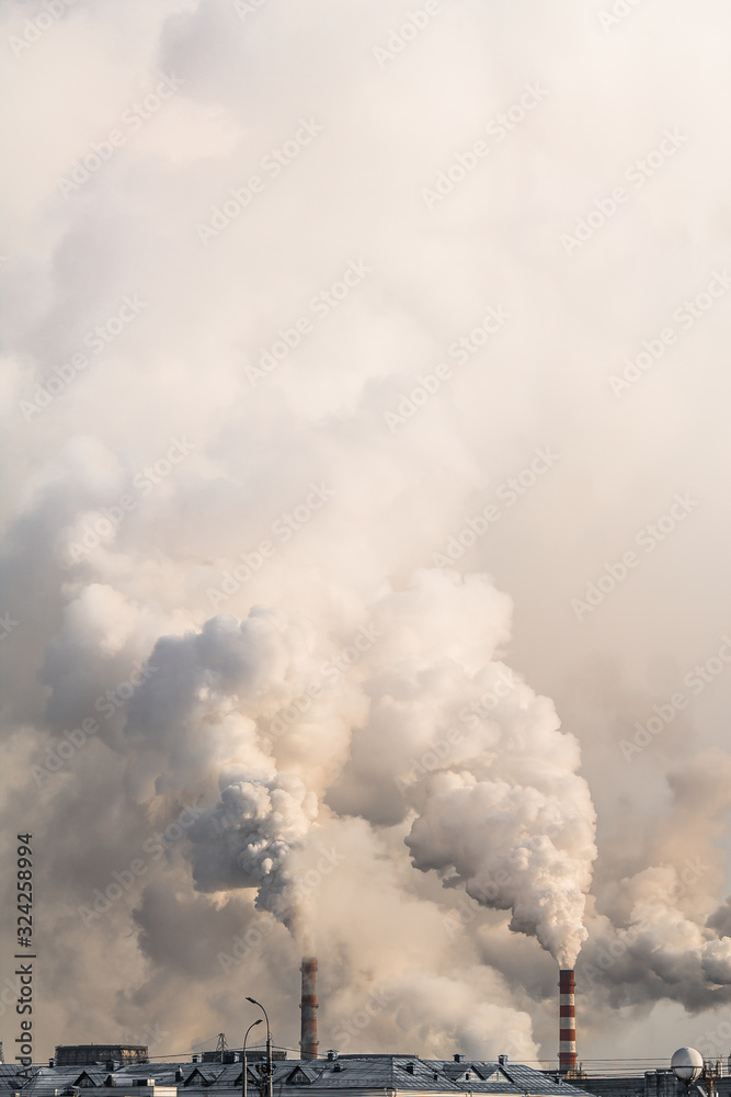 Vertical banner of industrial chimneys with heavy smoke causing air pollution on gray sky background