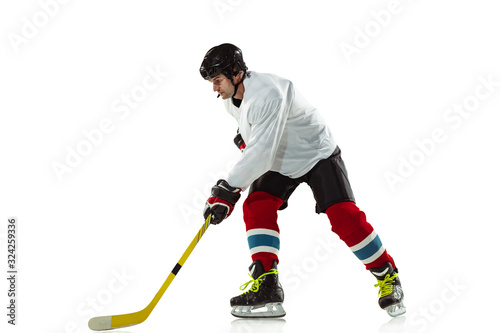 Target. Young male hockey player with the stick on ice court and white background. Sportsman wearing equipment and helmet practicing. Concept of sport, healthy lifestyle, motion, movement, action.