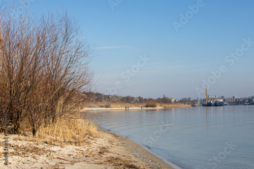 sandy riverbank with city view in autumn afternoon © Евгений Вдовин