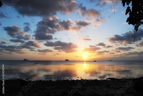 Wide shot of a tropical island sunset with beautiful clouds reflected in the sea