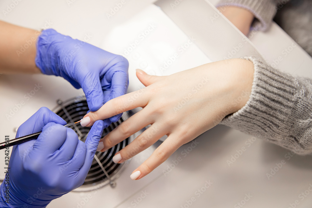 Fototapeta premium Master applies varnish drawing on nails gel in manicure salon