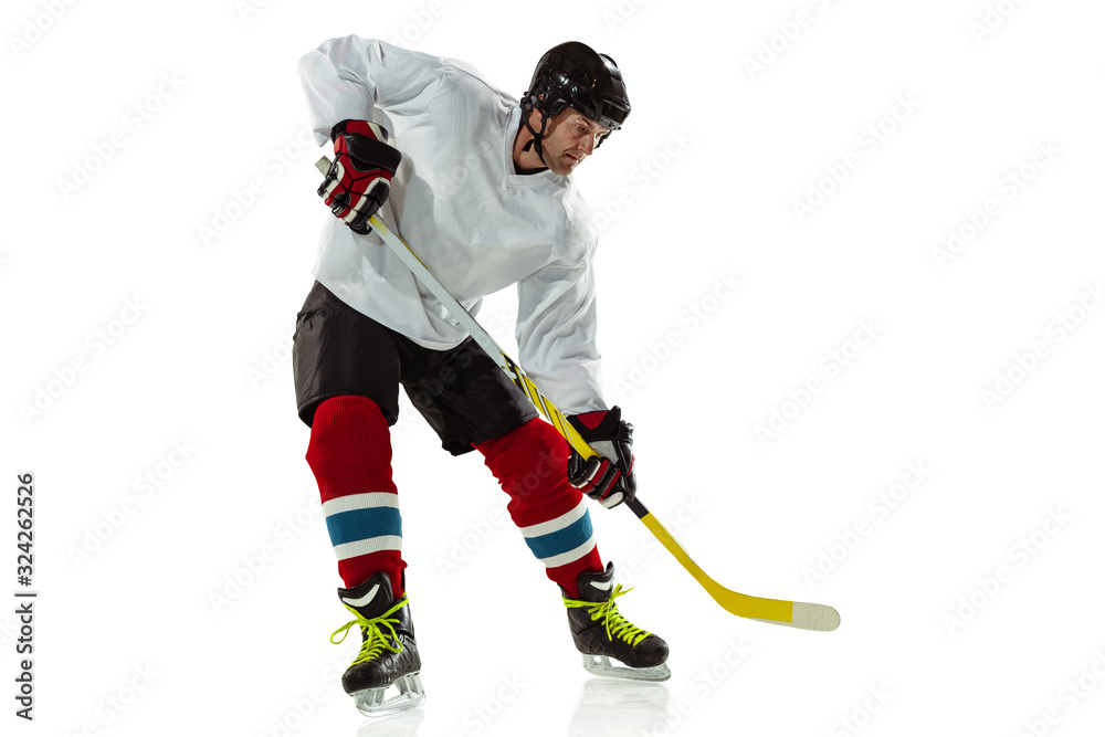 Fototapeta premium Activity. Young male hockey player with the stick on ice court and white background. Sportsman wearing equipment and helmet practicing. Concept of sport, healthy lifestyle, motion, movement, action.