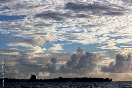 Large wads of cottony clouds over the silhouette of Saipan in the Northern Mariana Islands at sunset.