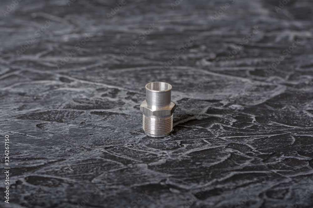 Union - a pipe for connecting piping, tanks, valves and other parts of gas and liquid transmission and converting systems. Lying on a textured concrete surface Union - a pipe for connecting piping, tanks, valves and other parts of gas and liquid transmission and converting systems. Lying on a textured concrete surface