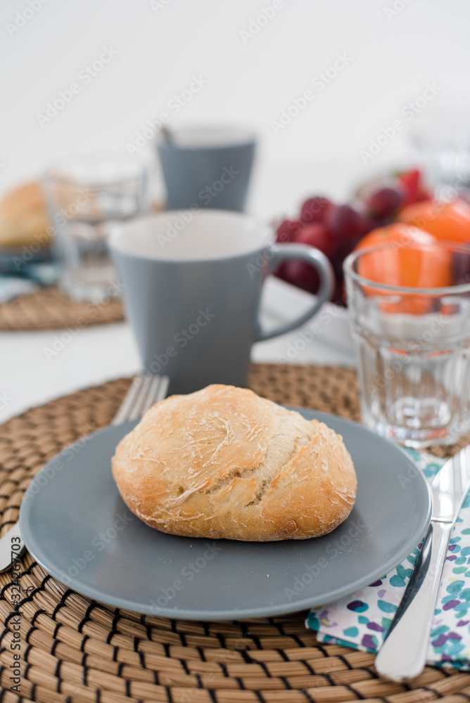 Plate with fresh crusty bread and glass of juice on grey plate Plate with fresh crusty bread and glass of juice on grey plate
