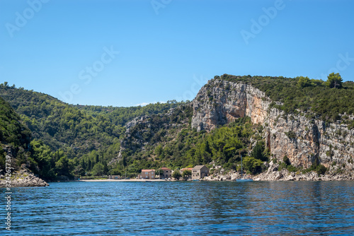 Beautiful small bay with several traditional stone houses, turquoise blue waters and a moored yacht, Pokrivenik bay, Island of Hvar, Croatia.