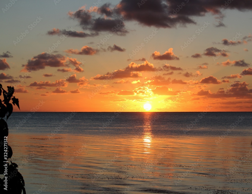 Golden sunset breaking over the sea and casting reflections in the water Golden sunset breaking over the sea and casting reflections in the water