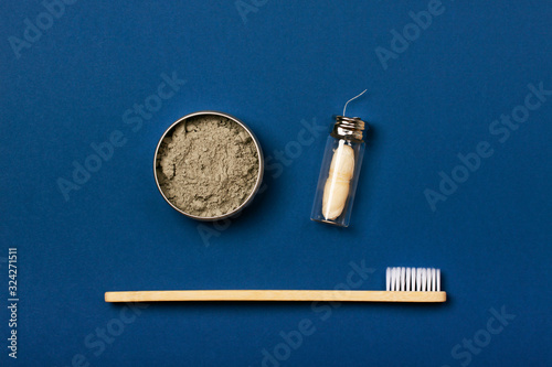 Set of eco-friendly tooth care items on the blue background. Bamboo toothbrush, organic tooth powder and natural dental floss. Zero waste concept, plastic-free, organic, eco-friendly shopping photo