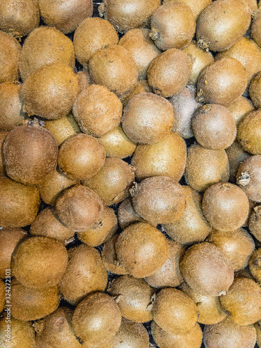 Juicy unpeeled kiwi fruits lie in a heap. Background image.