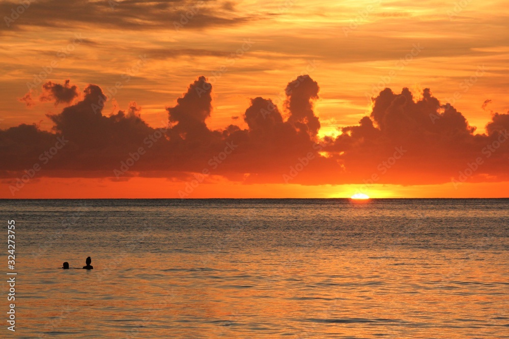 Dramatic cloud formations and flaming orange skies reflected in the sea at sunset