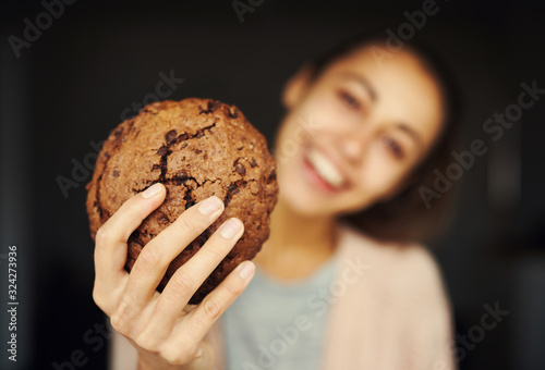 happy smiling woman holding huge chocolate cookie, focus on cookie. food, sweets and bakery concept.