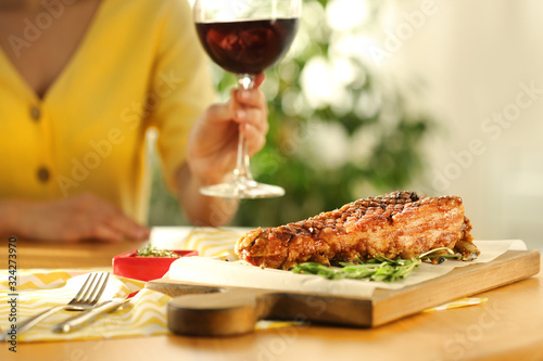 Woman having lunch in restaurant, focus on delicious roasted ribs