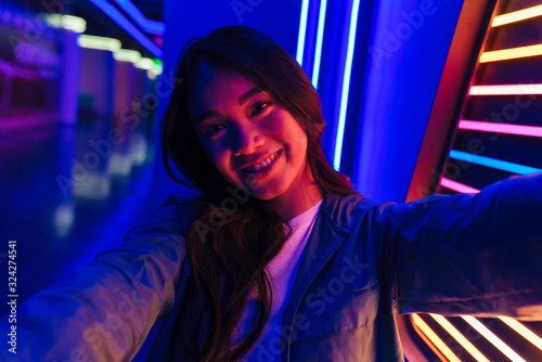 Happy optimistic positive woman posing over neon lights
