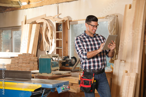 Professional carpenter with tablet in modern workshop