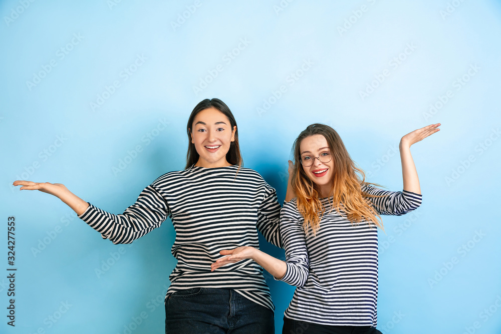 Inviting, greeting. Young emotional women isolated on gradient blue ...