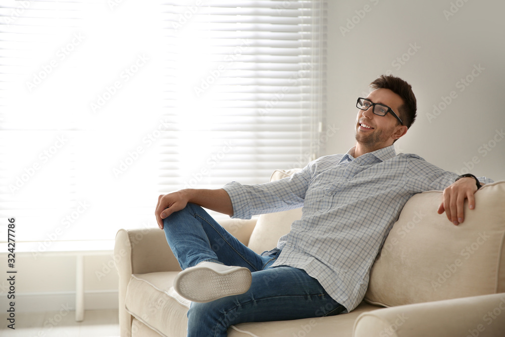 Young man relaxing on couch near window at home Young man relaxing on couch near window at home