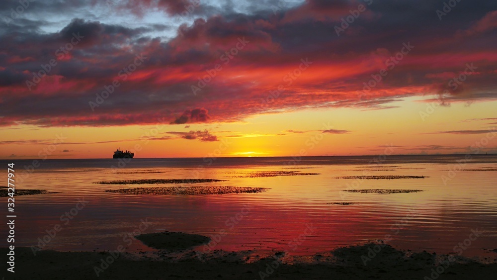 Spectacular and dramatic clouds reflected in the sea at sunset, with the silhoutte of a ship in the far distance. Spectacular and dramatic clouds reflected in the sea at sunset, with the silhoutte of a ship in the far distance.