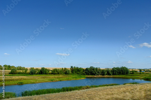 A small rural pond against a blue sky
