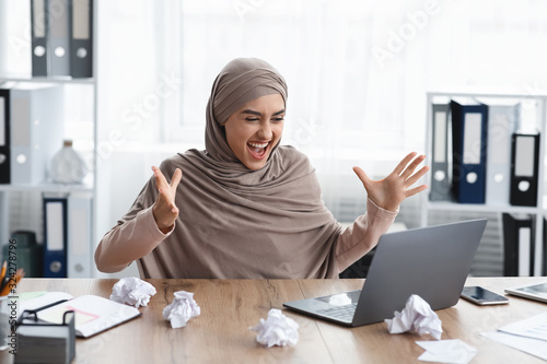 Euphoric businesswoman looking at laptop screen, happy after completing job