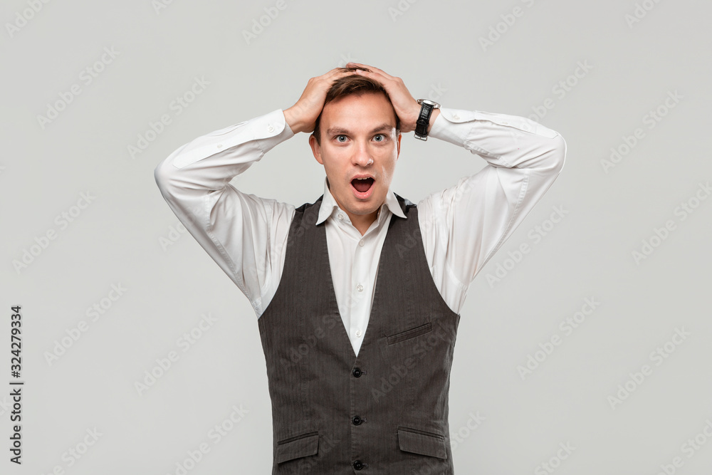 Handsome man in a white shirt and grey vest clutches head because he faces some problems. Handsome man in a white shirt and grey vest clutches head because he faces some problems.