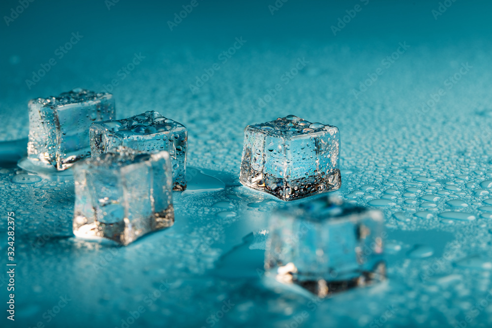 Ice cubes are scattered with water drops scattered on a blue background. Ice cubes are scattered with water drops scattered on a blue background.