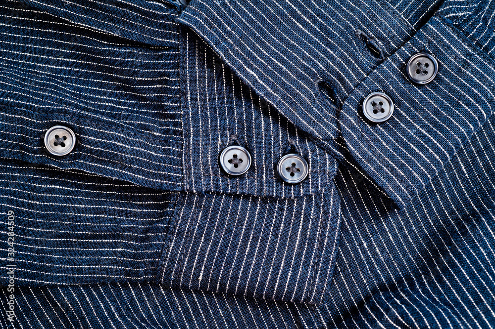 The texture of a denim shirt in dark blue with a small strip on the buttons. Background for fabric and clothes. Fashion, style and practicality.
