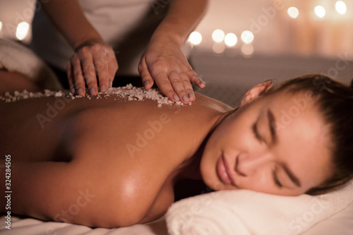 Quadro em tela Beauty therapist pouring salt scrub on womans back