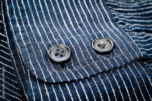The texture of a denim shirt in dark blue with a small strip on the buttons. Background for fabric and clothes. Fashion, style and practicality.