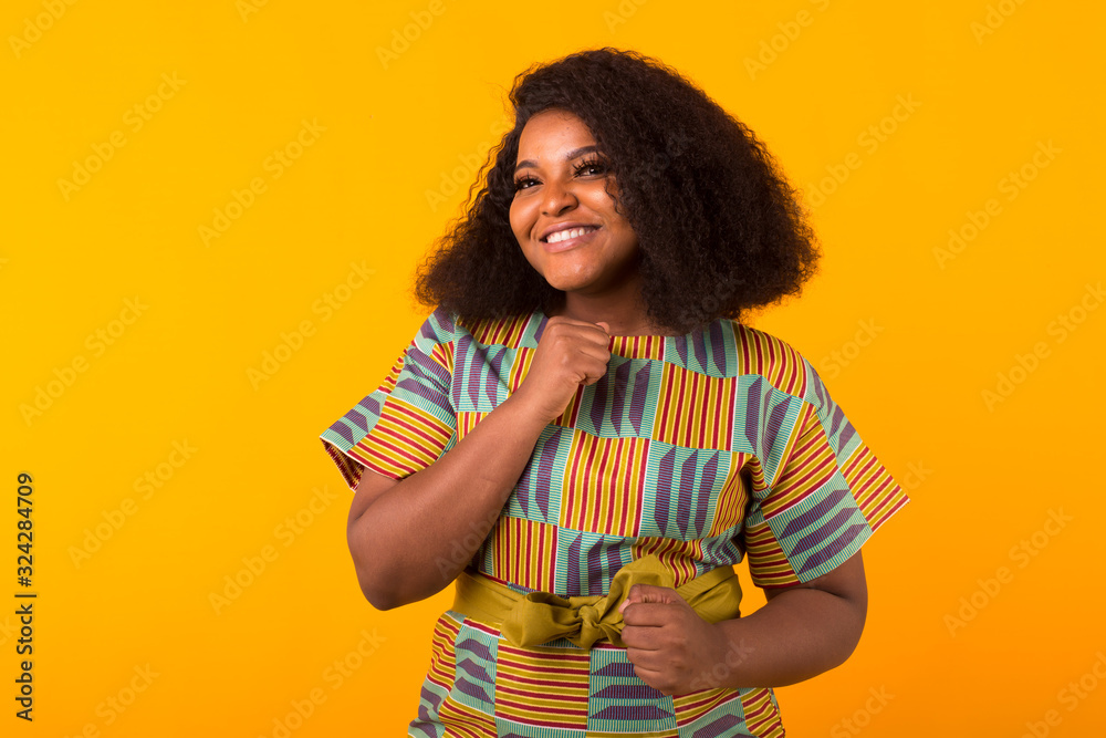 Young beautiful african american girl with an afro hairstyle. Portrait on yellow background. Young beautiful african american girl with an afro hairstyle. Portrait on yellow background.