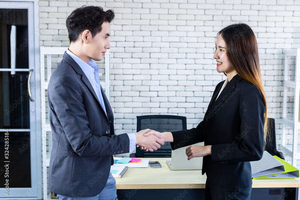 Asian businesswoman and businessman shaking hands at In the office room background after the contract is signed or handshake greeting deal,business expressed confidence embolden and successful couple Asian businesswoman and businessman shaking hands at In the office room background after the contract is signed or handshake greeting deal,business expressed confidence embolden and successful couple