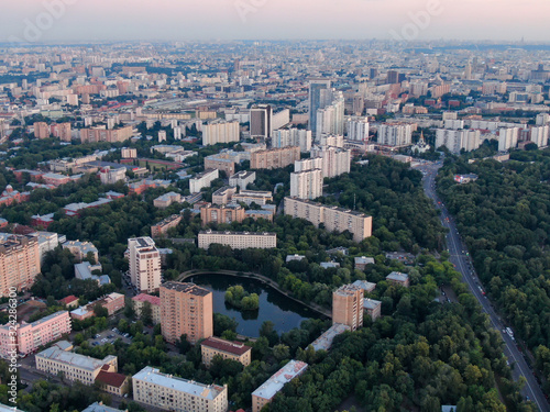 Evening Moscow from above, in the frame of a house and a street, a lake in the yard of a house and a road with cars, city everyday life. Aerial photography