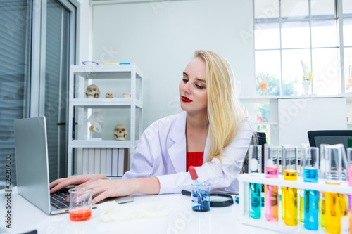 portrait of a female researcher carrying working with laptop computer and out research in a chemistry lab scientist holding test tube with sample in Laboratory analysis background