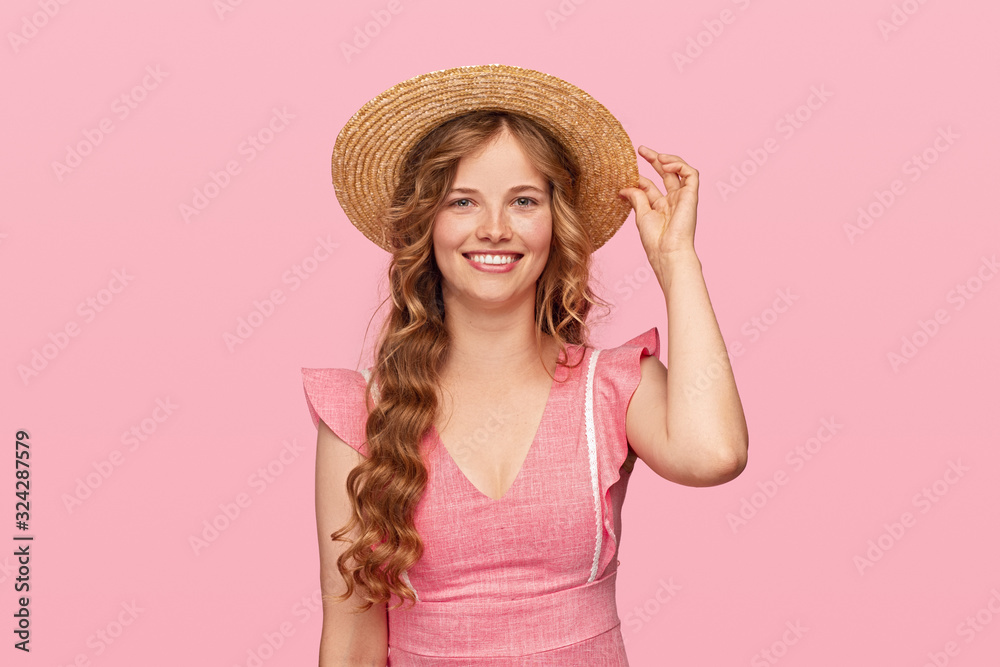 Cheerful Slavic woman adjusting straw hat