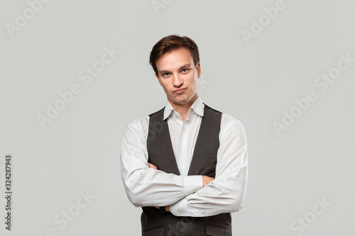 Young businessman in a white shirt and grey vest feels confident holding hand crossed