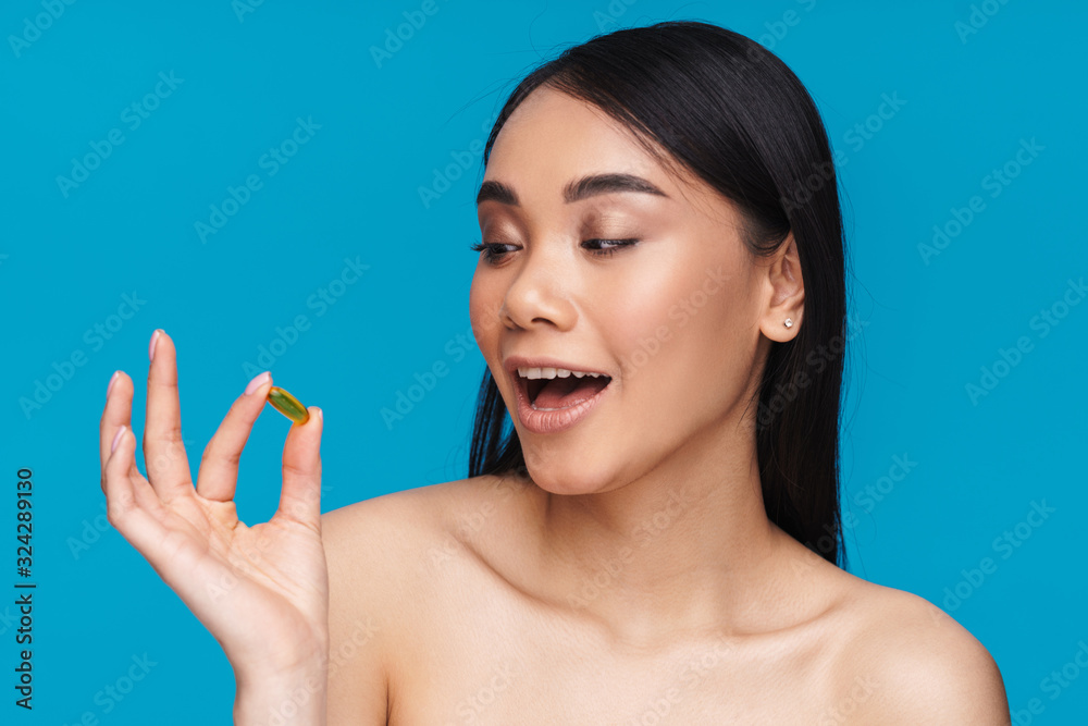 Woman posing isolated holding vitamin pill. Woman posing isolated holding vitamin pill.
