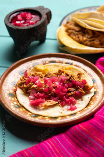 Mexican pork tacos also called "Cochinita pibil" on turquoise background