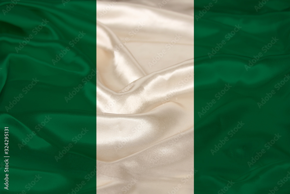 Obraz premium photo of the national flag of Nigeria on a luxurious texture of satin, silk with waves, folds and highlights, closeup, copy space, travel concept, economy