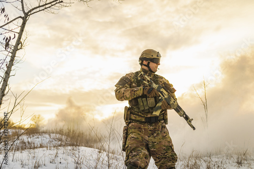 equipped army soldier Man in the winter khaki camouflage is patrolling or patrol field territory. commandos with full equipment helmet and gun watch battlefield. Modern army soldier