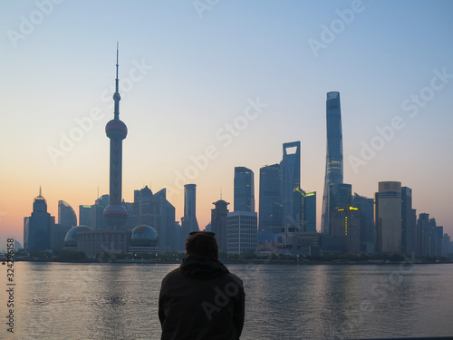 Back view of a man contemplating a beautiful sunrise over pudong view from the Bund in shanghai