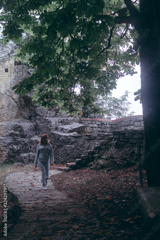 Woman Posing against the backdrop of the fortress, steps, stairs. Mystical atmosphere, fog and mist. Vertical photo. Pass of the witches San Marino (Passo delle streghe, Monte Titano)