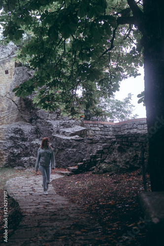 Woman Posing against the backdrop of the fortress, steps, stairs. Mystical atmosphere, fog and mist. Vertical photo. Pass of the witches San Marino (Passo delle streghe, Monte Titano)