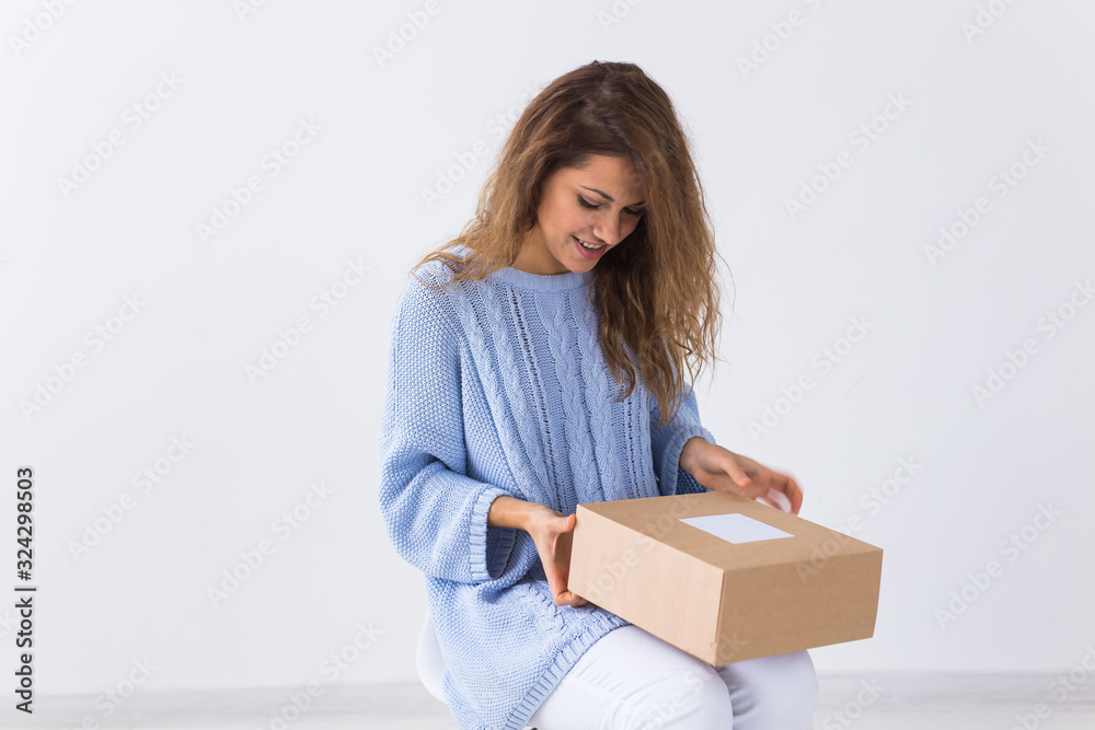 Online shopping, delivery and fashion concept - Woman sitting on sofa at home opening online clothing purchase Online shopping, delivery and fashion concept - Woman sitting on sofa at home opening online clothing purchase