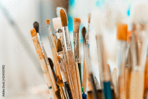 Tools and equipment for the artist. Palette and brushes close-up. The process of drawing and creativity. The picture is in blue.