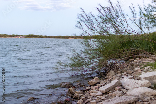 A large lake  the banks are strewn with huge stones. On the lake on a summer evening. Lake Casa Blanca  Texas  USA