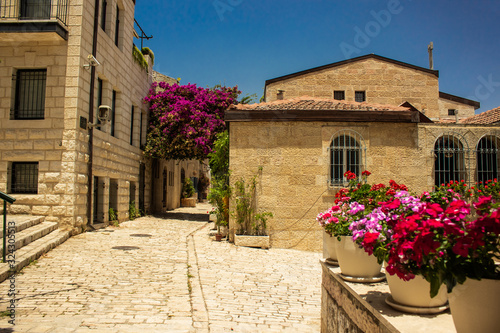 Fototapeta Naklejka Na Ścianę i Meble -  Jerusalem Israeli ancient city street landmark urban view paves road and stone small building and flowers vases landscaping outside environment in sunny summer clear weather day without people here