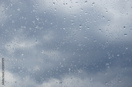 Regentropfen Wassertropfen auf Fensterscheibe mit Wolken Himmel im Hintergrund