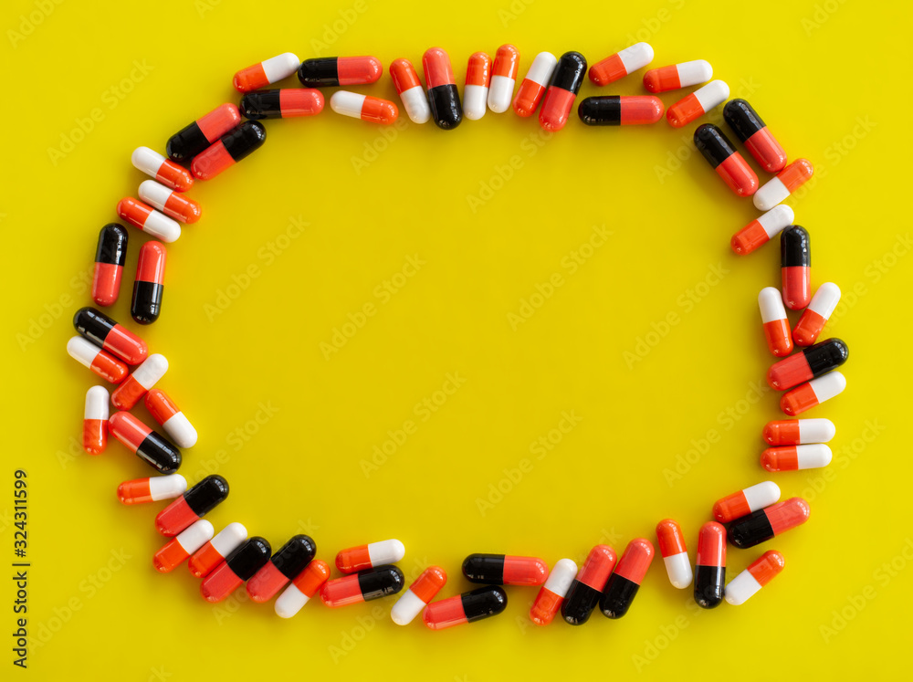 Obraz premium Capsules of medicine are located around the perimeter on a yellow background with an empty place for text in the center, top view