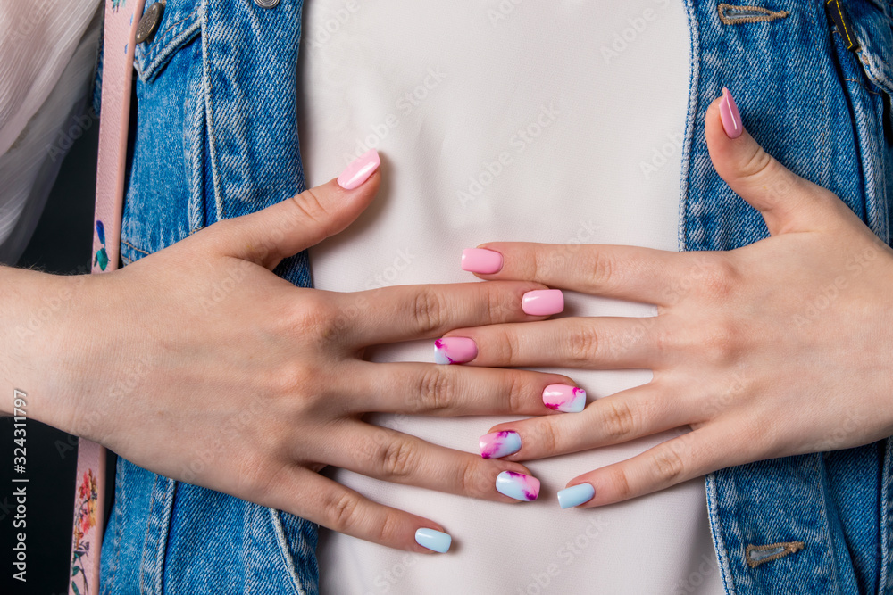 Fototapeta premium Hands of a girl with multicolored nails lying on her stomach